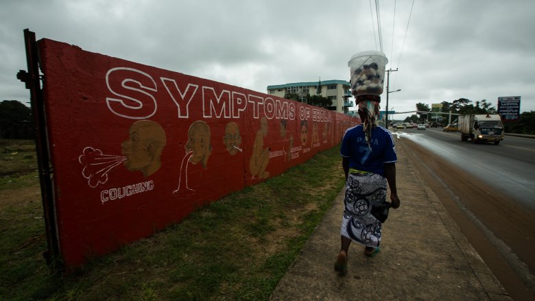 Woman walks past a wall with information on Ebola